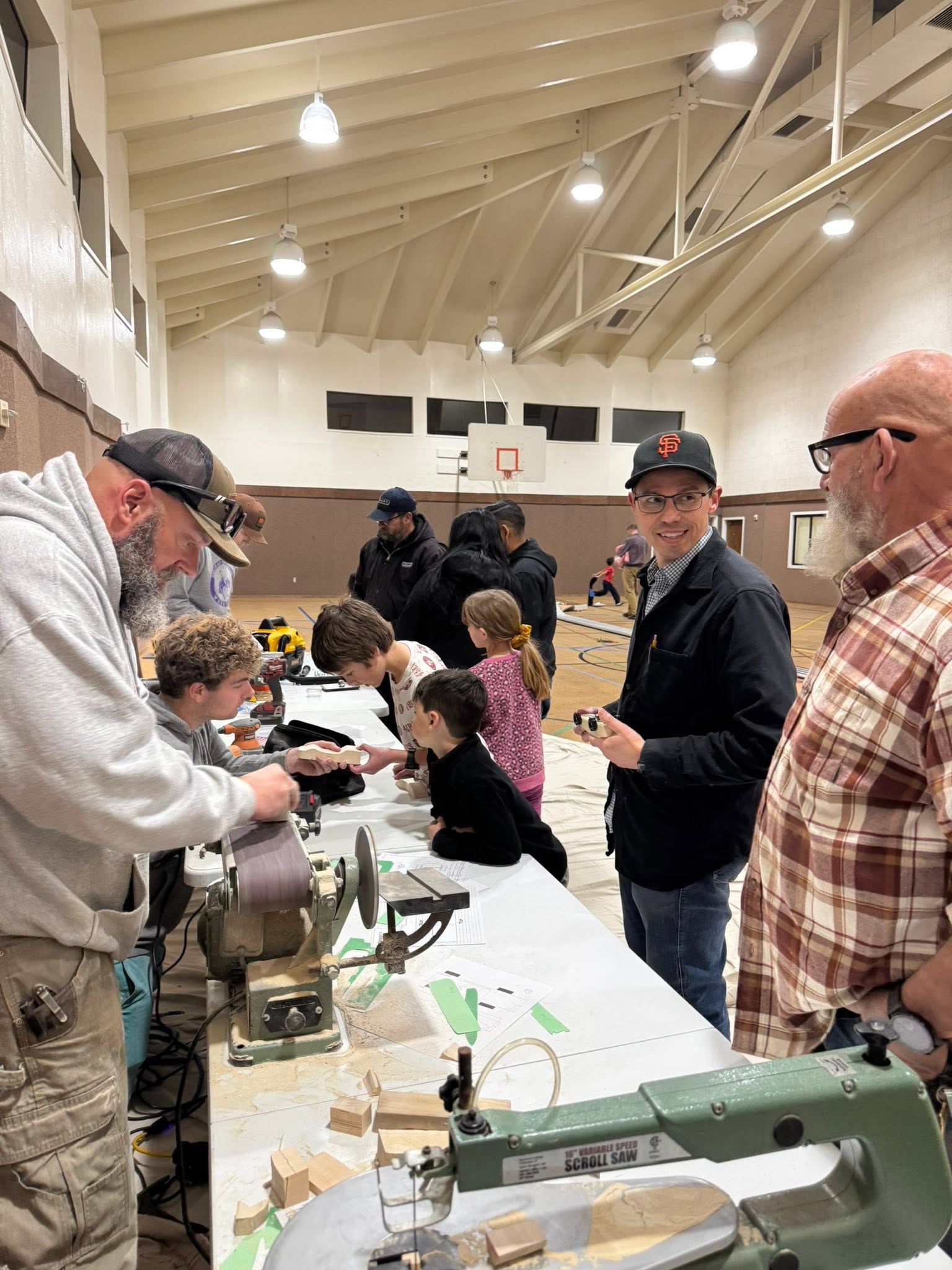 Families building pinewood derby cars in the church gym